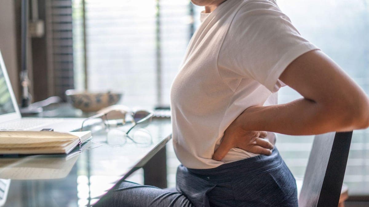 Persona con dolor lumbar sentada frente al computador